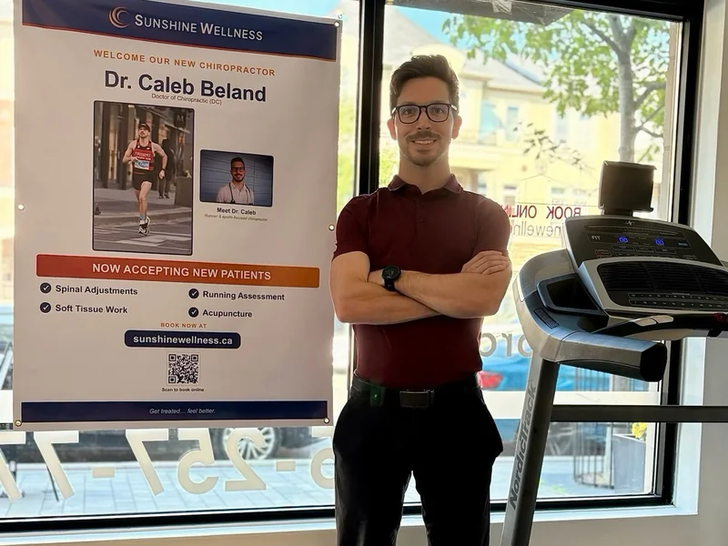 Dr. Caleb Beland beside the in-clinic treadmill at Sunshine Wellness in Oakville